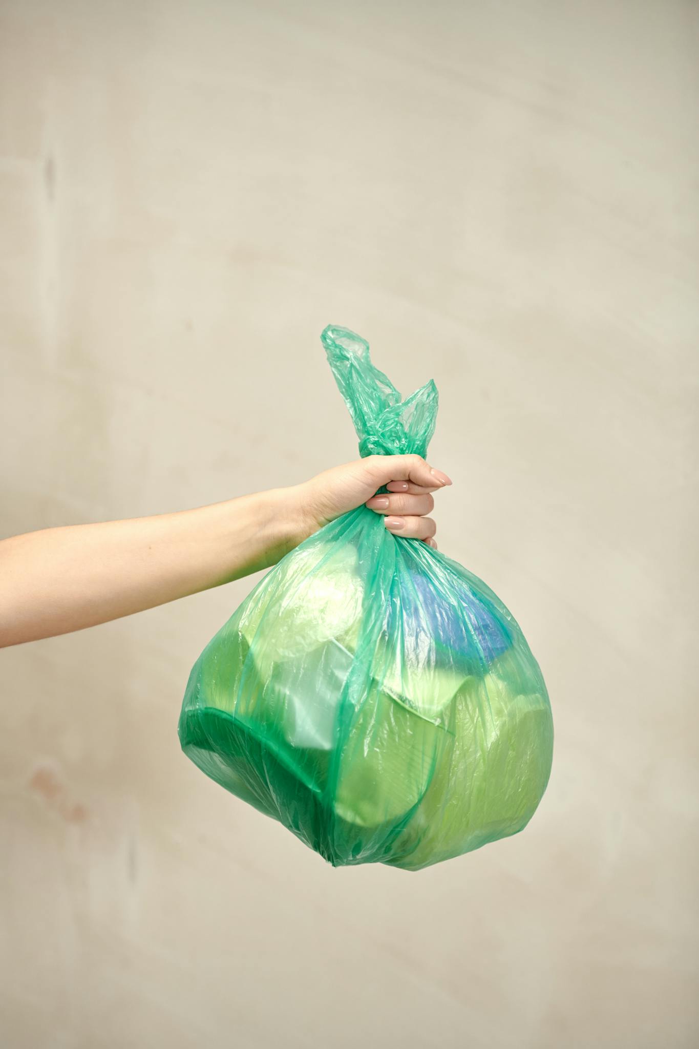 A Person Holds A Green Plastic Bag