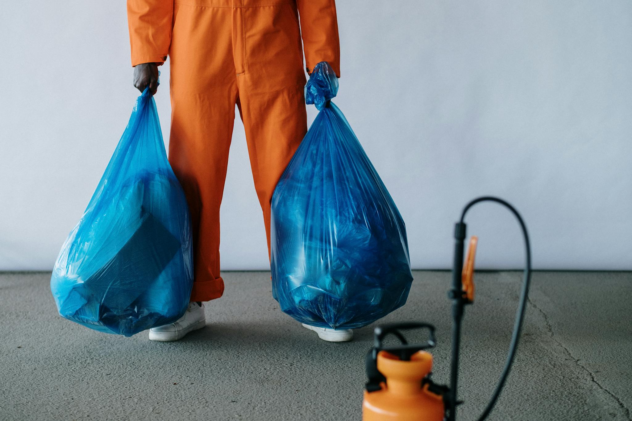 Sanitation Worker In Orange Overalls Holding Blue